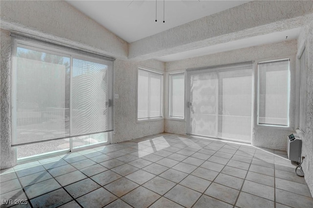 unfurnished room with light tile patterned floors, a wall unit AC, and a textured wall