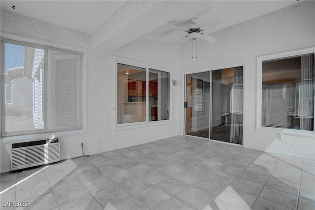 unfurnished sunroom featuring a wall mounted air conditioner and ceiling fan