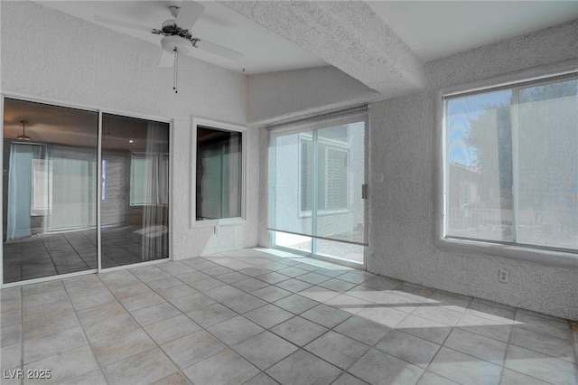 unfurnished room with tile patterned flooring, plenty of natural light, and a textured wall