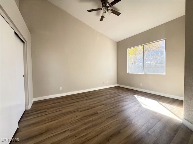 unfurnished bedroom featuring baseboards, vaulted ceiling, a closet, a ceiling fan, and dark wood-style flooring