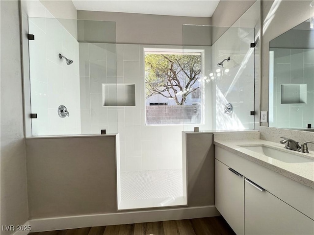 bathroom featuring vanity, wood finished floors, and walk in shower