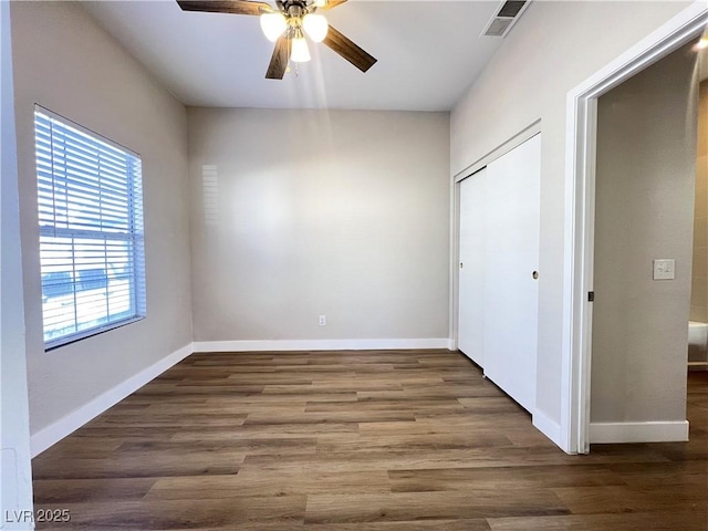 unfurnished bedroom featuring wood finished floors, a ceiling fan, a closet, visible vents, and baseboards