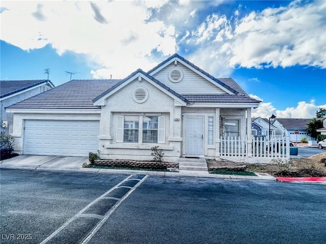 view of front of home with a tiled roof, an attached garage, driveway, and stucco siding