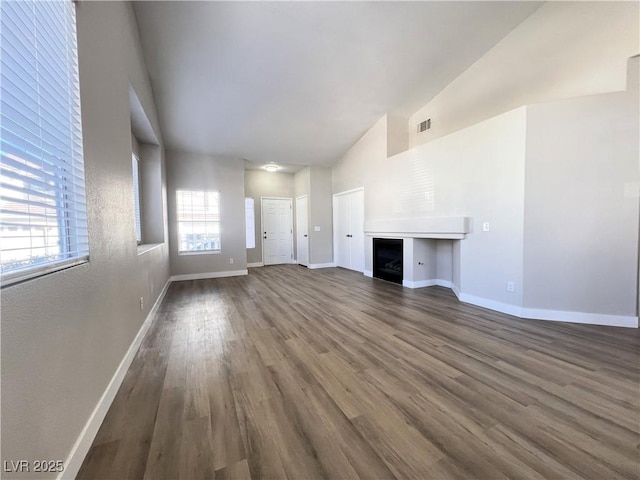 unfurnished living room featuring wood finished floors, a fireplace, baseboards, and visible vents