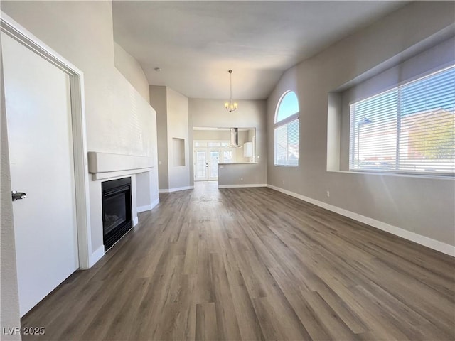 unfurnished living room with dark wood-style flooring, baseboards, and a glass covered fireplace