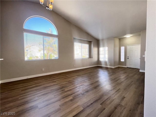 unfurnished living room featuring lofted ceiling, a notable chandelier, baseboards, and dark wood finished floors