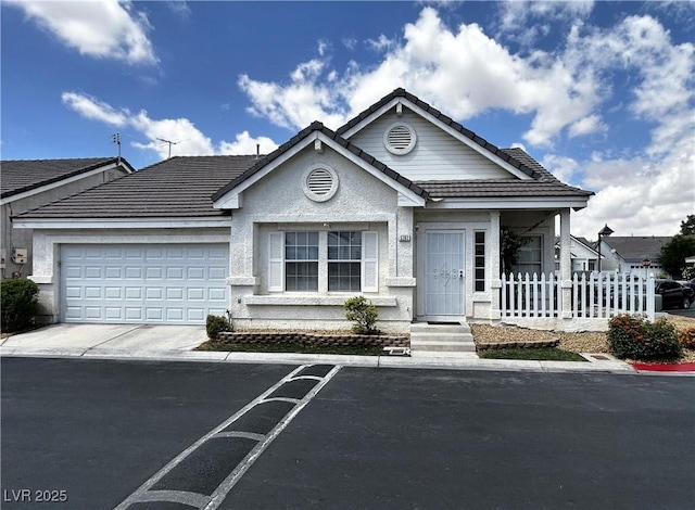 view of front of house featuring driveway, a tiled roof, fence, a garage, and stucco siding