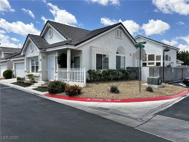 view of front of property with a garage, stucco siding, a tile roof, and fence