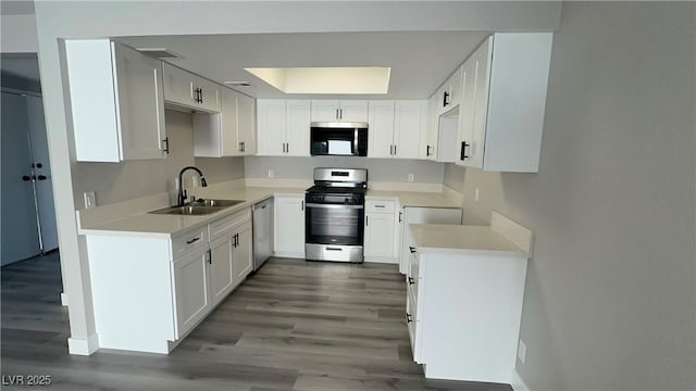 kitchen with a sink, light wood-style floors, white cabinetry, and stainless steel appliances