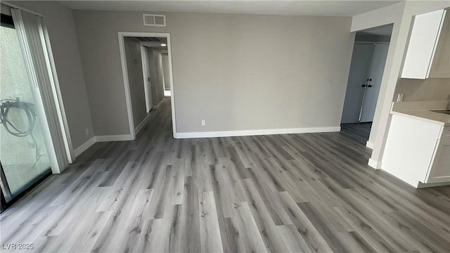 unfurnished living room featuring light wood-type flooring, baseboards, and visible vents