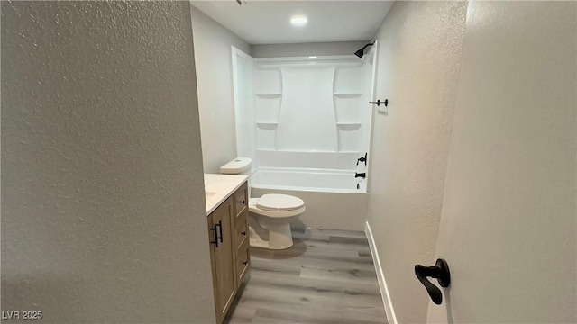 full bath featuring vanity, wood finished floors, shower / tub combination, toilet, and a textured wall