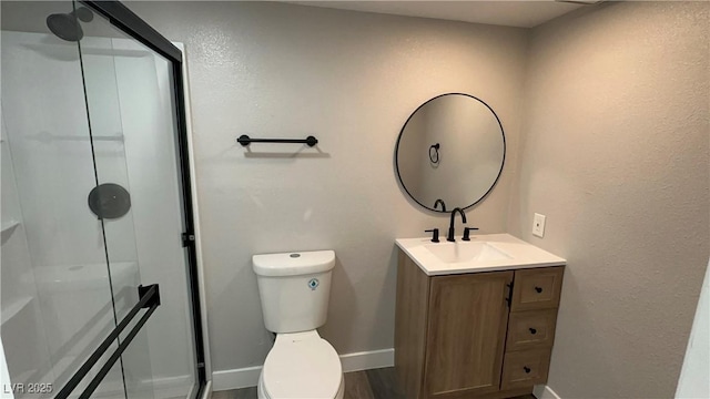 full bath with vanity, a shower stall, toilet, and baseboards