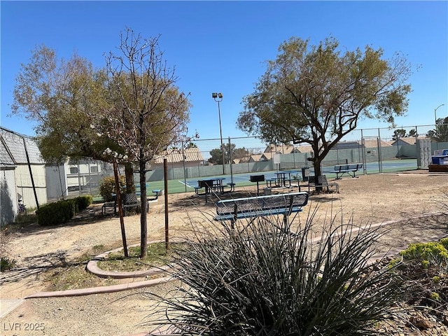 surrounding community with a tennis court and fence