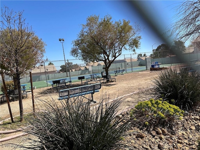 view of home's community with a tennis court and fence