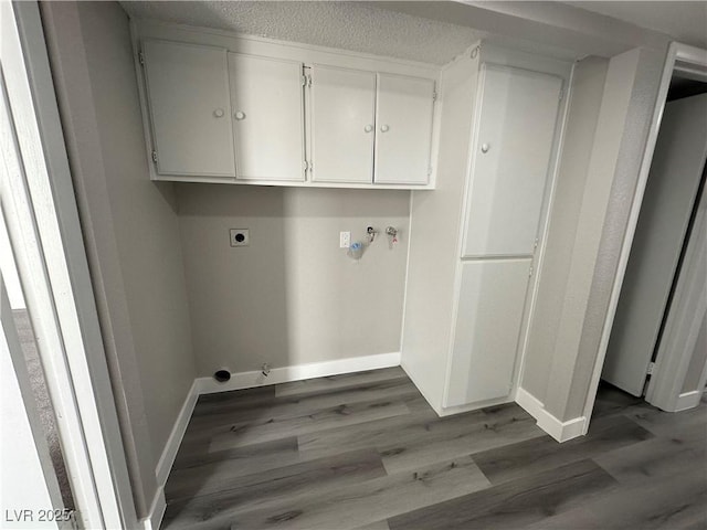 laundry area with electric dryer hookup, baseboards, cabinet space, and dark wood-style flooring