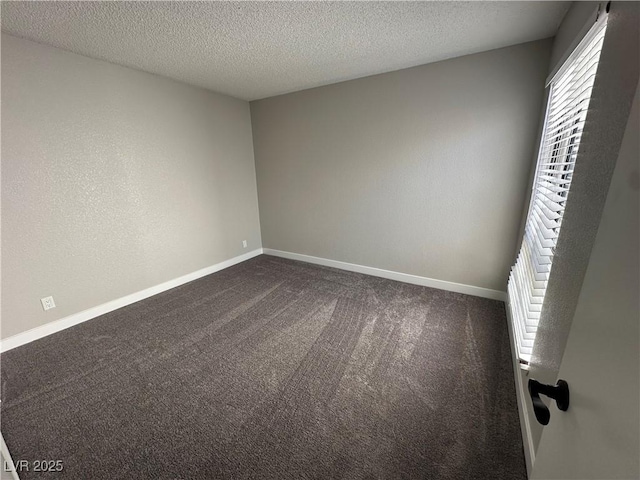 empty room featuring a textured ceiling, baseboards, and dark colored carpet