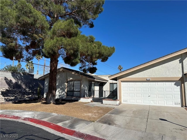 view of front of house with stucco siding, an attached garage, driveway, and fence