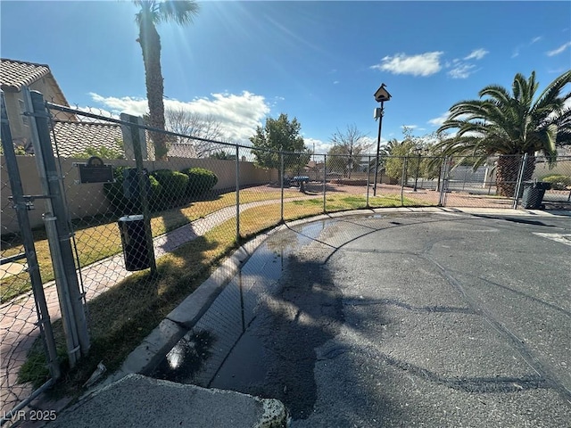 view of street featuring curbs, street lighting, and a gate