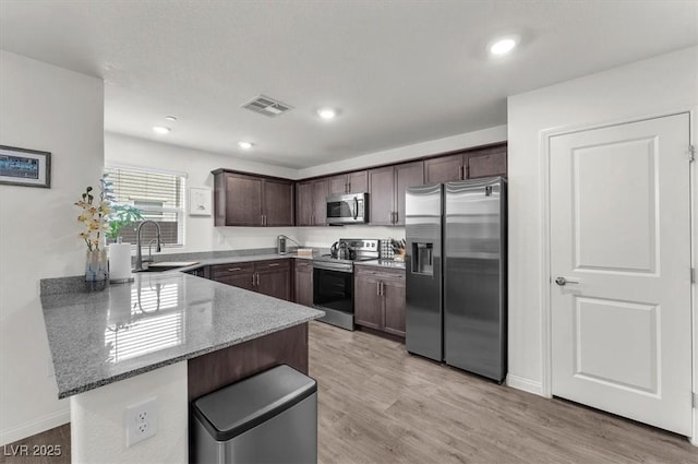 kitchen with visible vents, a sink, appliances with stainless steel finishes, a peninsula, and dark brown cabinets