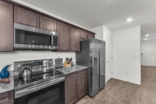 kitchen featuring light stone counters, baseboards, light wood finished floors, dark brown cabinetry, and appliances with stainless steel finishes