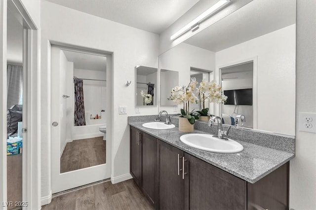 full bathroom featuring double vanity, toilet, wood finished floors, and a sink