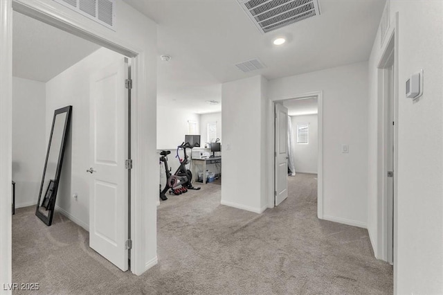 corridor featuring a wealth of natural light, visible vents, carpet floors, and baseboards