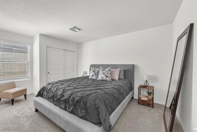 bedroom with baseboards, carpet, visible vents, and a textured ceiling