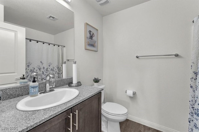 bathroom with vanity, wood finished floors, visible vents, baseboards, and toilet