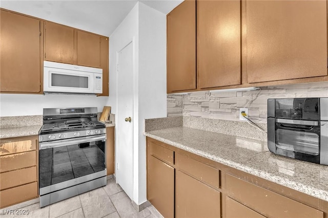 4153 Broadriver Dr, Las Vegas, NV 89108 - kitchen featuring tasteful backsplash, a toaster, white microwave, and stainless steel gas stove