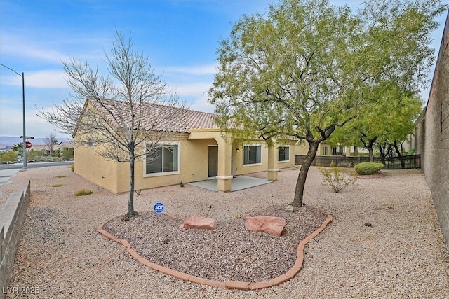 back of house with a tiled roof, stucco siding, fence, and a patio area