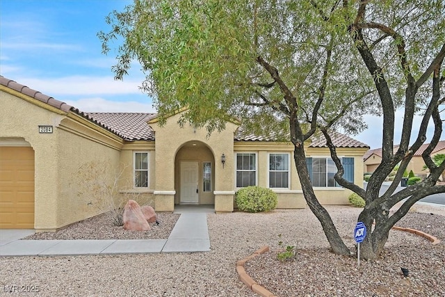 mediterranean / spanish house with stucco siding, a tiled roof, and a garage