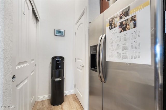 interior space featuring light wood-type flooring, baseboards, and stainless steel refrigerator with ice dispenser