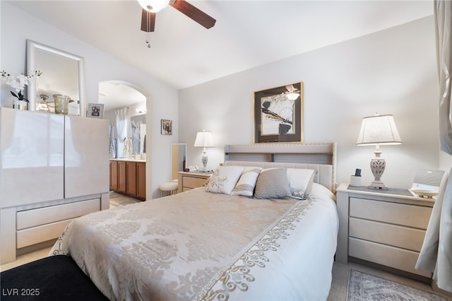 bedroom with connected bathroom, arched walkways, a ceiling fan, and vaulted ceiling