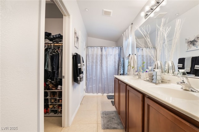 full bath with a sink, visible vents, double vanity, and tile patterned floors