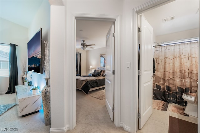 hallway featuring light tile patterned floors, visible vents, and light carpet