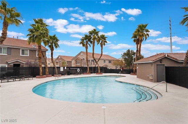 pool with a residential view, a patio, and fence