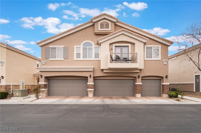 mediterranean / spanish house with stucco siding, a balcony, a garage, and a tiled roof