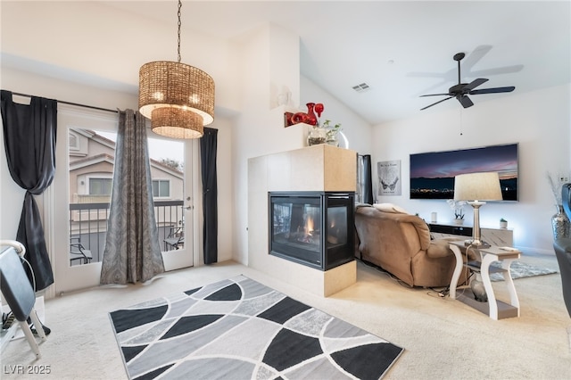 living room with visible vents, a multi sided fireplace, carpet flooring, ceiling fan with notable chandelier, and high vaulted ceiling