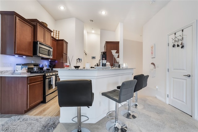 kitchen with visible vents, recessed lighting, a peninsula, appliances with stainless steel finishes, and a breakfast bar area