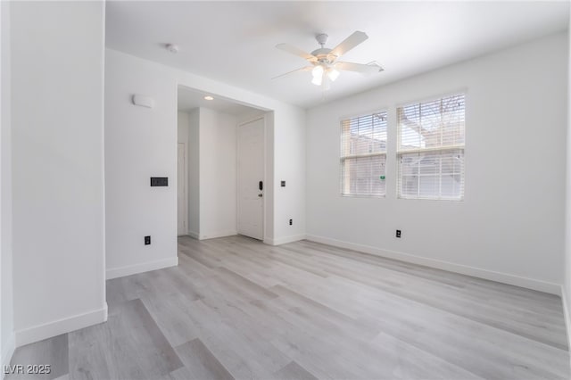 spare room with light wood finished floors, a ceiling fan, and baseboards