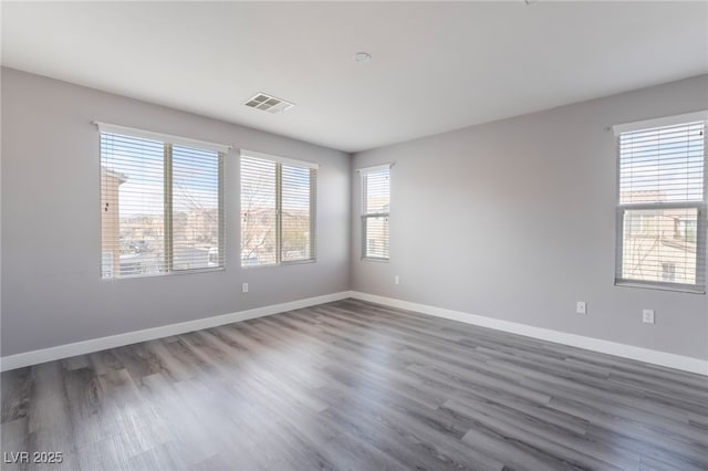 unfurnished room with wood finished floors, baseboards, and visible vents