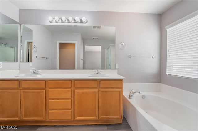 full bathroom with a bath, double vanity, and a sink