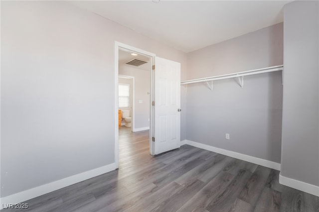 unfurnished bedroom featuring visible vents, baseboards, and wood finished floors