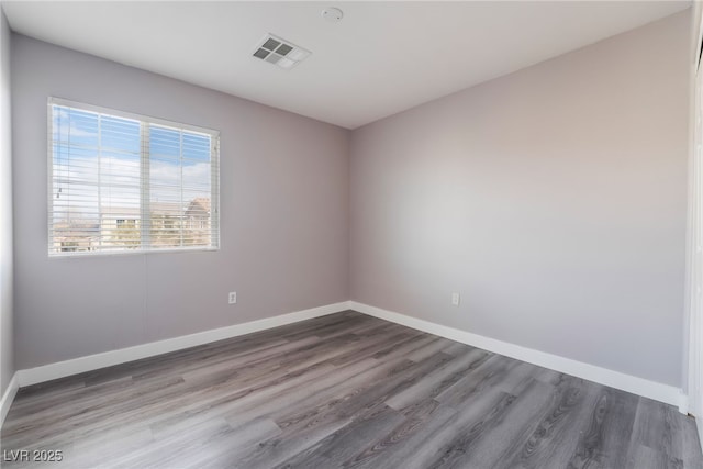 empty room with visible vents, baseboards, and wood finished floors