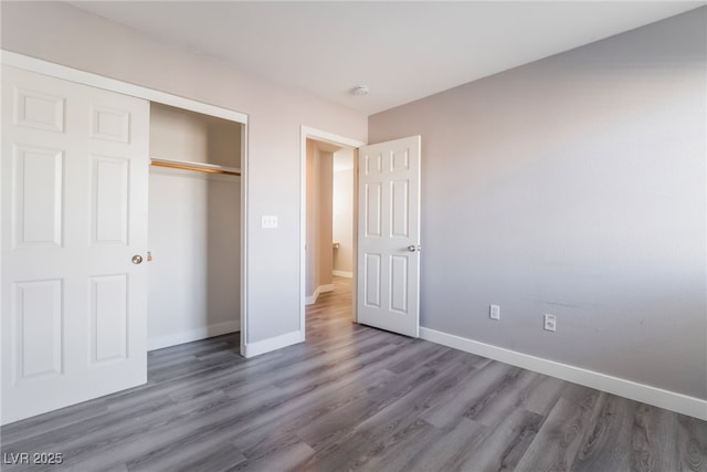 unfurnished bedroom with wood finished floors, baseboards, and a closet