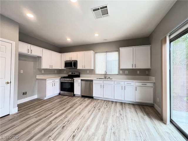 kitchen with visible vents, a sink, appliances with stainless steel finishes, white cabinets, and light countertops