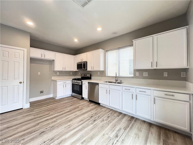 kitchen with visible vents, light wood-style flooring, appliances with stainless steel finishes, white cabinetry, and a sink