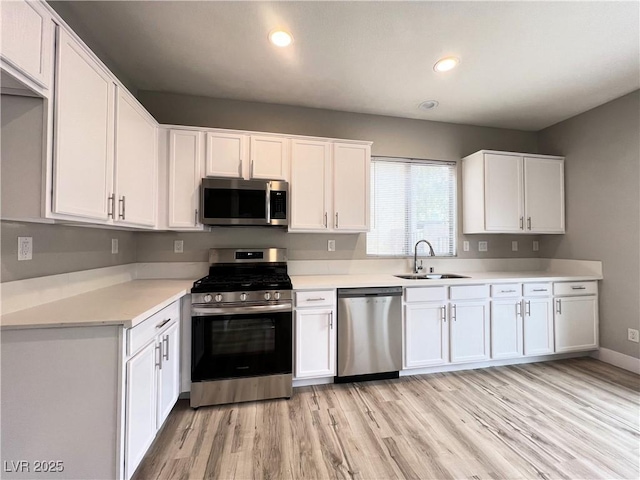 kitchen with light countertops, white cabinets, appliances with stainless steel finishes, and a sink