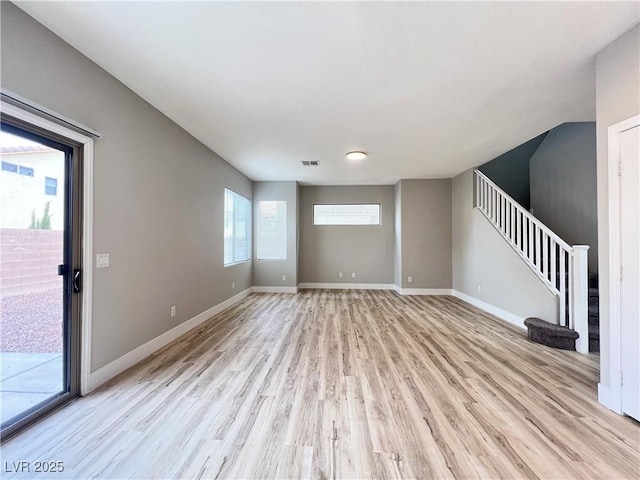 unfurnished living room featuring stairway, visible vents, light wood-type flooring, and baseboards