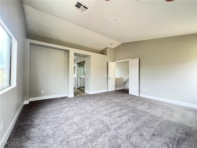 unfurnished bedroom featuring visible vents, baseboards, carpet, and lofted ceiling